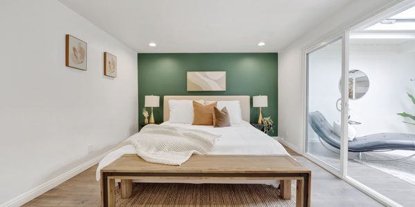 Minimalist bedroom with green accent wall and sliding glass doors.