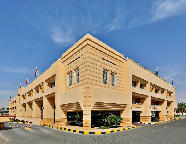 Modern beige building with flags and clear blue sky.