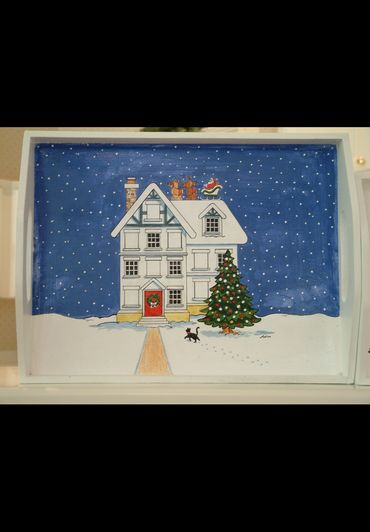 Painting of a snowy house with a Christmas tree and Santa on the roof.