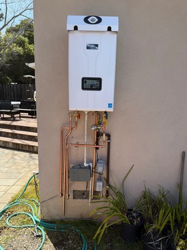 Outdoor tankless water heater installed on a wall.