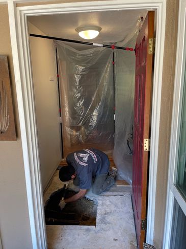 Worker fixing floor beneath a plastic barrier.