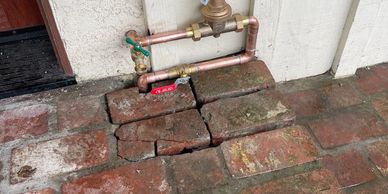 Old stone blocks with some plumbing pipes above. New pressure reducing valve and emergency shut off.