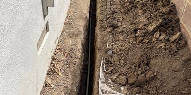 Narrow trench dug between two walls. With new water, plumbing service pipe. 