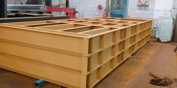 Large yellow industrial steel frames stacked in a workshop.