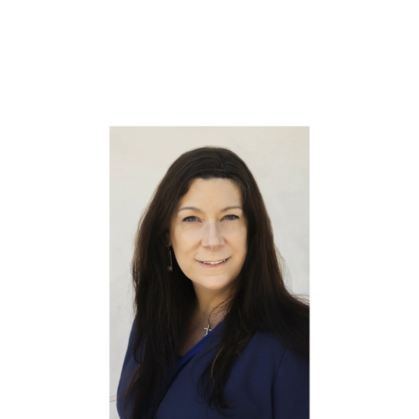 Professional woman with long dark hair wearing a blue blazer and cross necklace.
