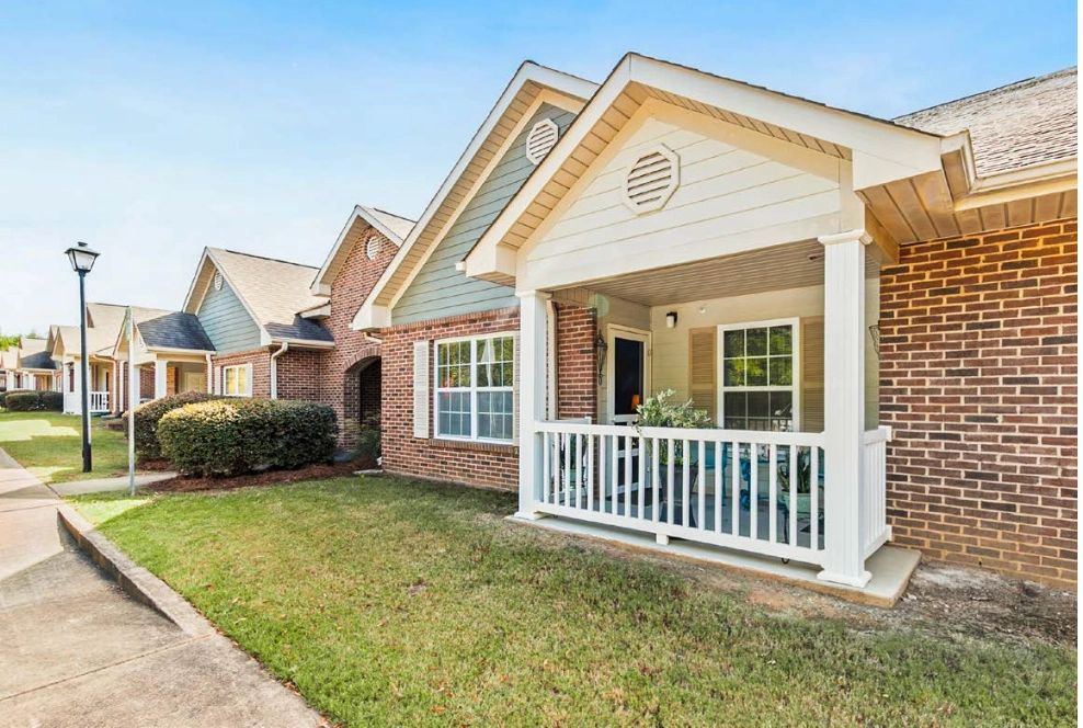 Row of charming brick townhouses with small porches and manicured lawns.