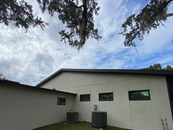 Backyard of a modern house with air conditioning units and garden tools.