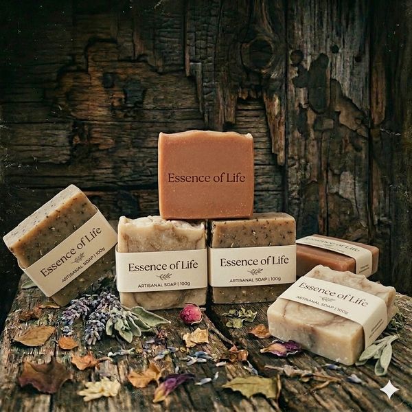 Artisanal soaps labeled 'Essence of Life' displayed on rustic wooden surface with dried flowers.