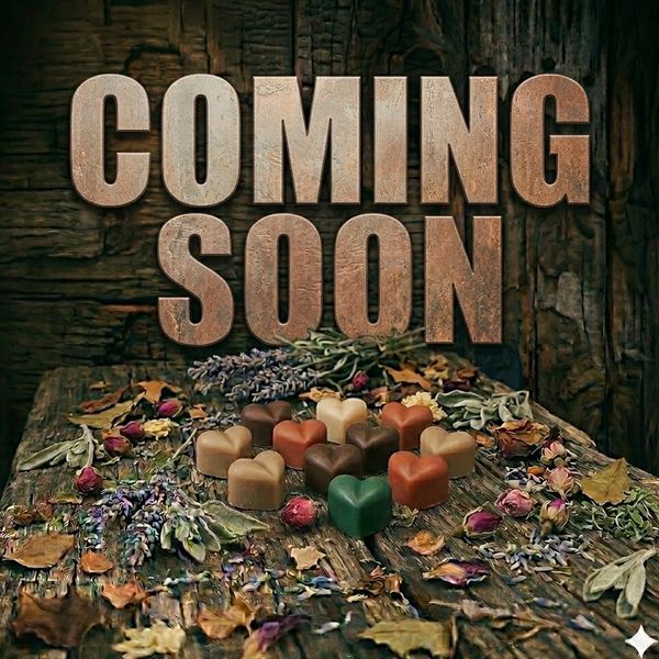 Rustic 'Coming Soon' text with heart-shaped chocolates and dried flowers on wooden surface.