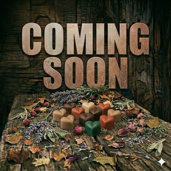 Rustic 'Coming Soon' text with heart-shaped chocolates and dried flowers on wooden surface.