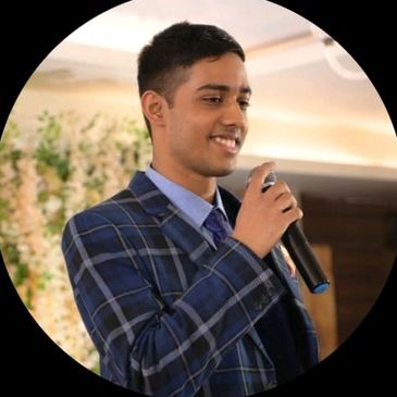 Young man in blue checkered suit speaking with a microphone.