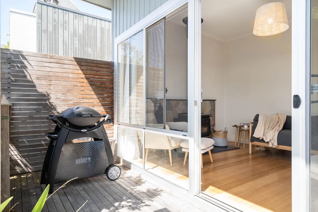 Sliding door from the deck leads to the lounge room. There is a black Weber BBQ on the deck.