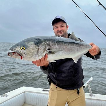 Man on boat proudly holds a large fish he caught.