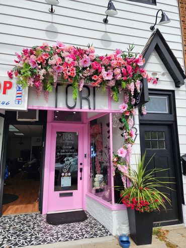 Flower-adorned pink storefront entrance with glass door.