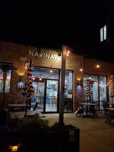 Night view of Narinata cafe with outdoor seating and string lights.