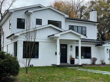 Modern white two-story house with large windows.