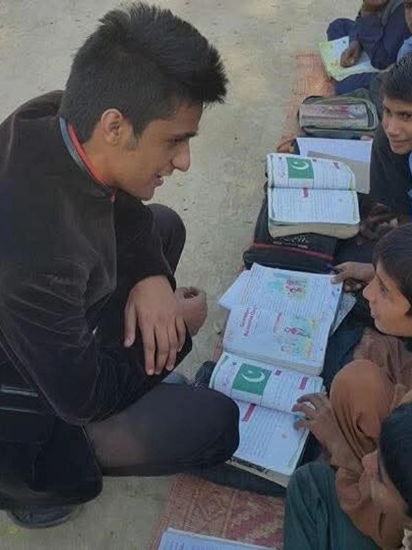 Young man teaching children outdoors with open books.