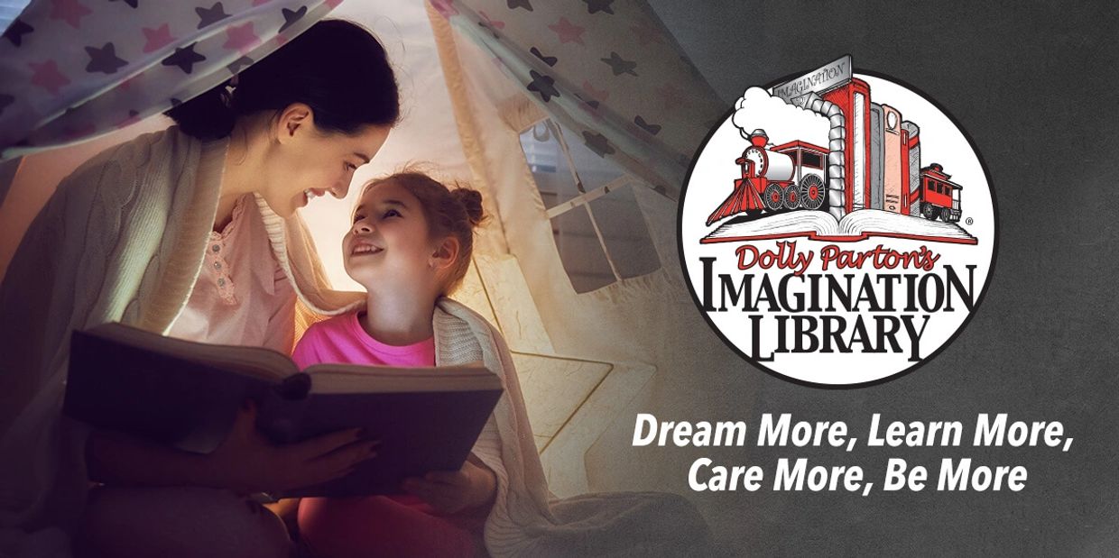 A woman and child reading together at home under a tent fort.