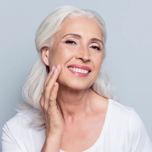 woman with grey hair touching smooth skin from chemcial peel