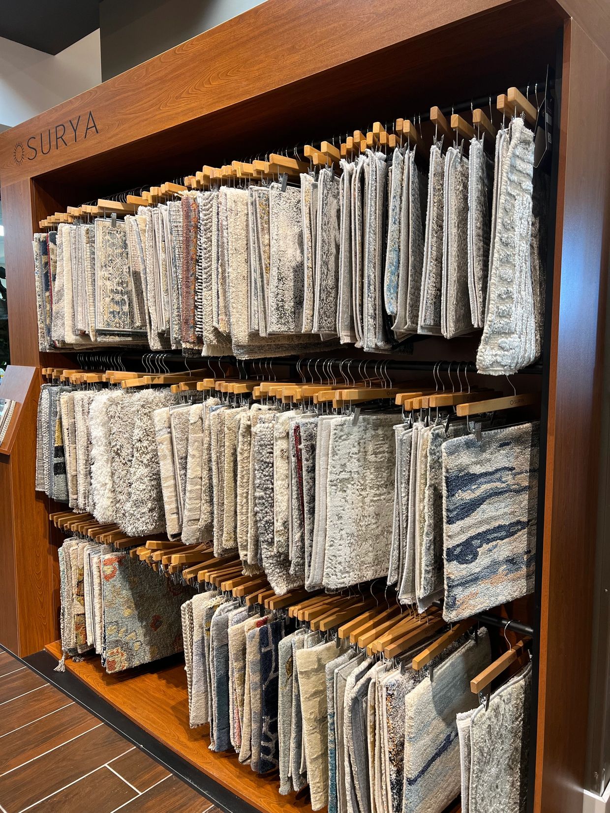 Display of carpet or rug samples hanging on wooden rods.