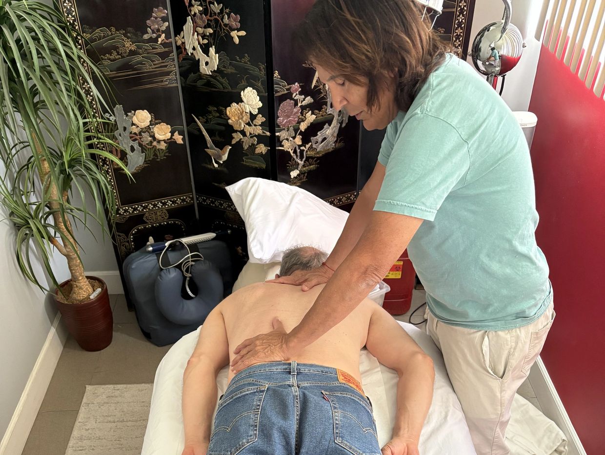 A woman giving a back massage to a man lying on a table.