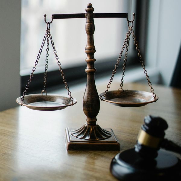 A wooden balance scale and a gavel on a table representing justice.