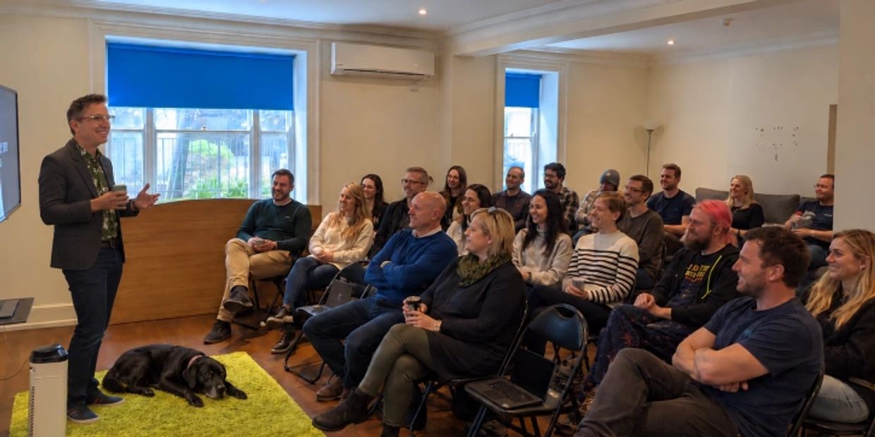 Iain Russell is giving a presentation to a seated group with his dog on the floor.
