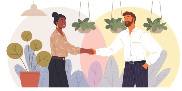 Two people shaking hands in a friendly, professional setting.