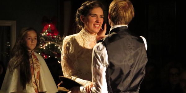 A woman in vintage clothing smiling at a man during a festive event.
