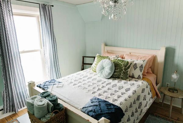 Cozy bedroom with patterned bedspread and decorative pillows.