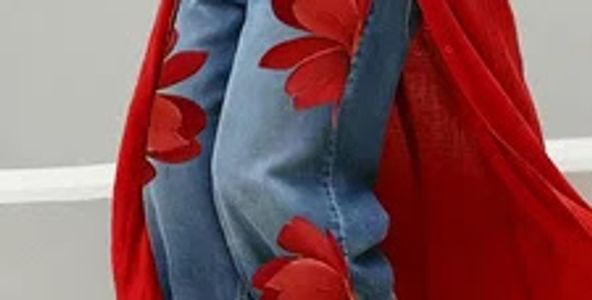 Denim jeans with large red floral patches and a flowing red garment.