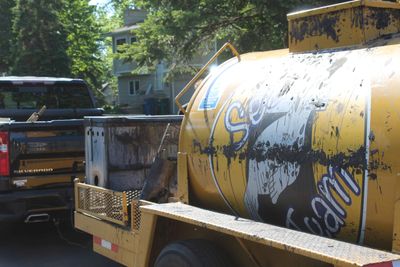 Old yellow water tank on trailer hitched to pickup truck.