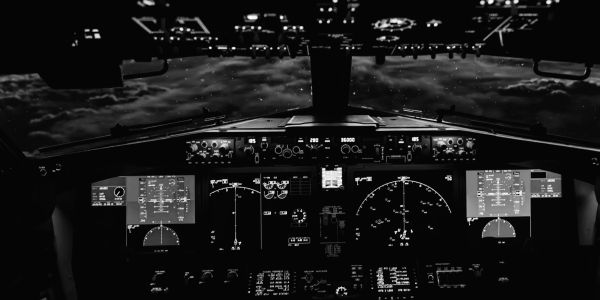 Black and white airplane cockpit view at night.