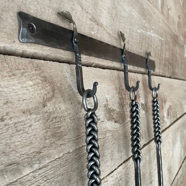 Hand-forged wrought iron wall rack with decorative twist hooks for fireplace set