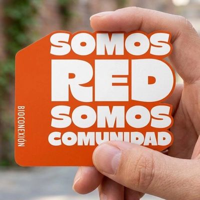 Hand holding an orange card with bold white text about community and connection.