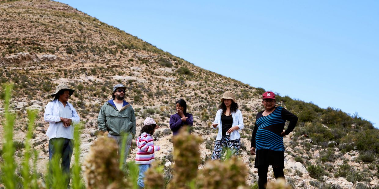 Group of six people standing in a desert landscape with hills.