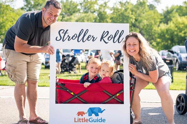 Family posing with a 'Stroller Roll' sign outdoors.