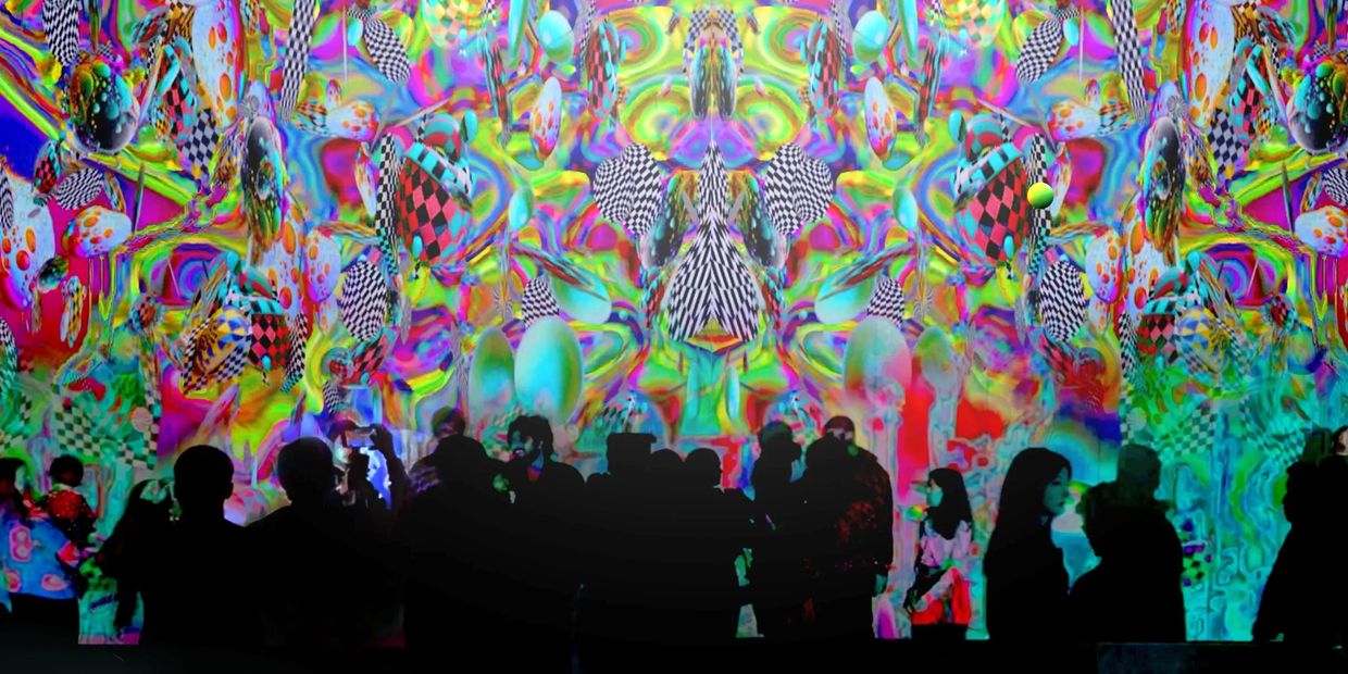 People in a colorful immersive art exhibit designed by  XO Immersive event production. Artist Robin 