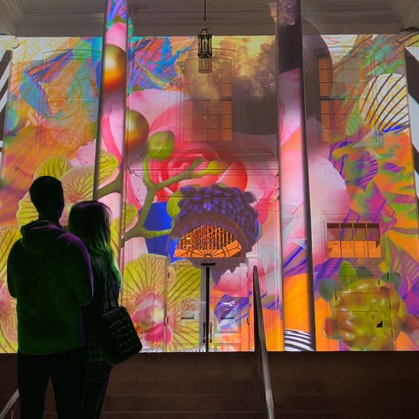 a couple stands looking at a projection mapping of a building in Cary North Carolina