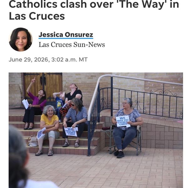 Women holding signs sit on stairs during a Catholic clash in Las Cruces.