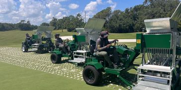 3 Drill and Fill aerators drilling and backfilling on a golf course green.