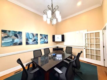 Modern conference room with glass table and black chairs.
