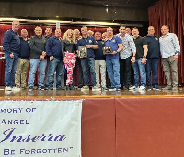 Group of people on stage holding plaques in memory of Angel Inserra.