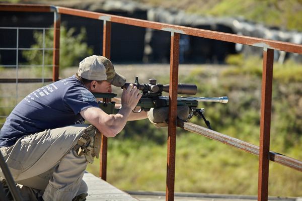 Man aiming a sniper rifle while kneeling.