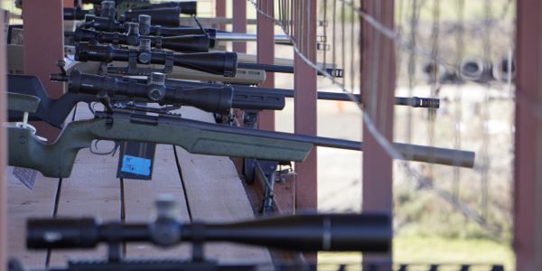 Row of sniper rifles lined up on a wooden rack.