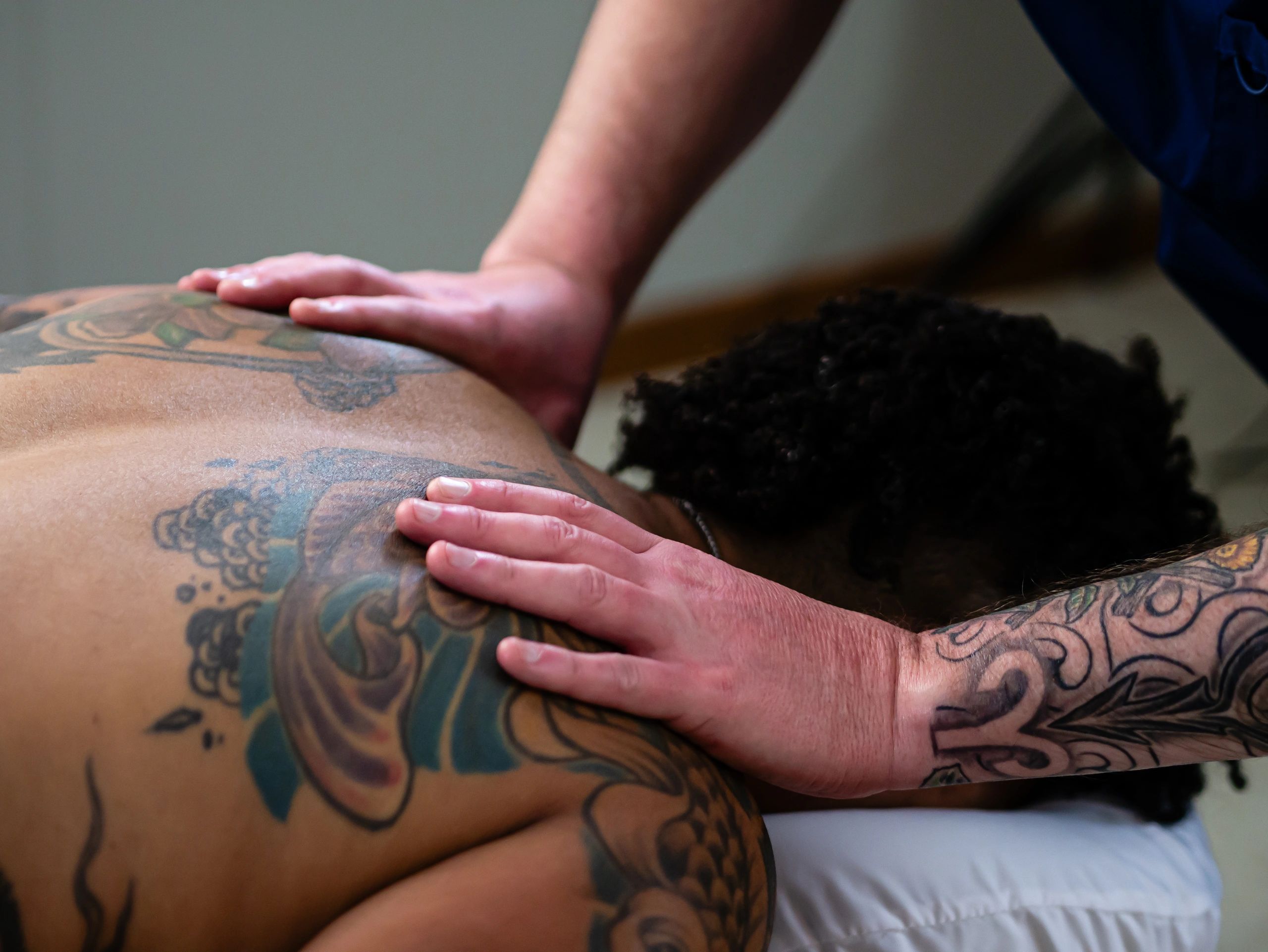 A person with melanated skin receives therapeutic massage from a licensed massage therapist.