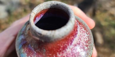 A soda-fired ceramic bottle with deep reds and grey/green glazes made by Darren Chittick