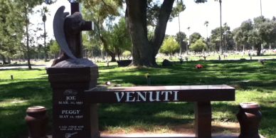 A unique memorial bench in a cemetery with the name 'VENUTI'.
