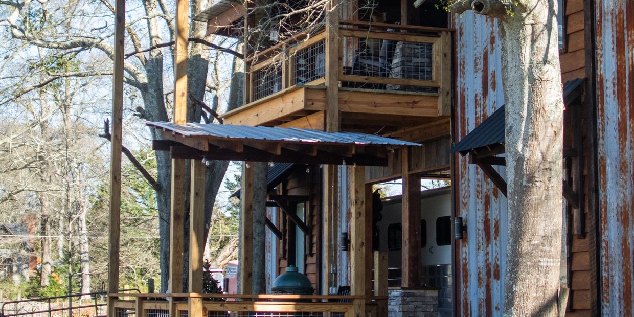 Rustic wooden building with a metal roof and outdoor deck surrounded by trees.
