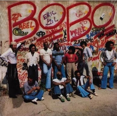 Group of men posing in front of a colorful graffiti wall with the word BOBO.